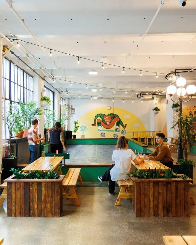 Indoor petanque court at Petanque Central with seating and vibrant wall art.