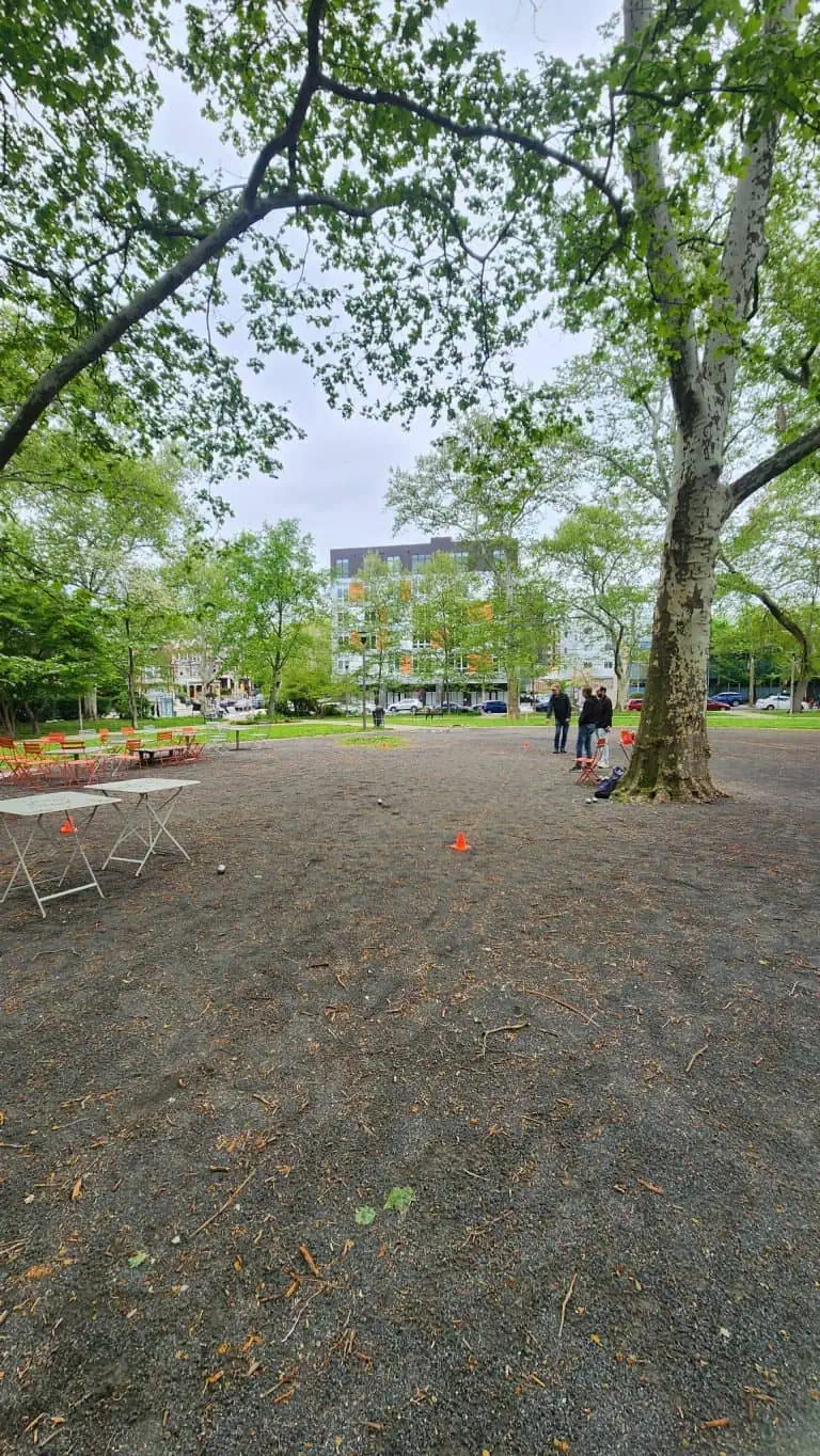 People playing pétanque in a lush green park in Philadelphia.