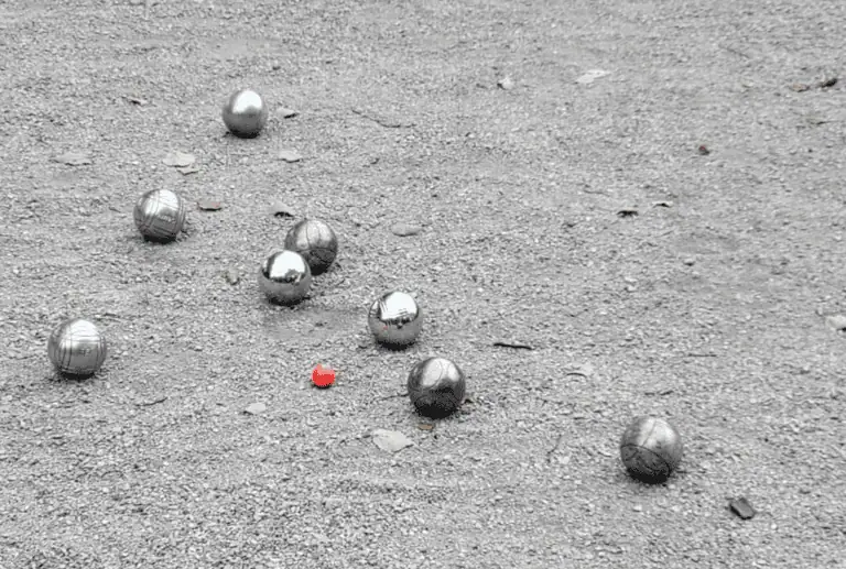 Boules de pétanque et cochonnet sur un terrain de gravier pour une partie à l’extérieur.
