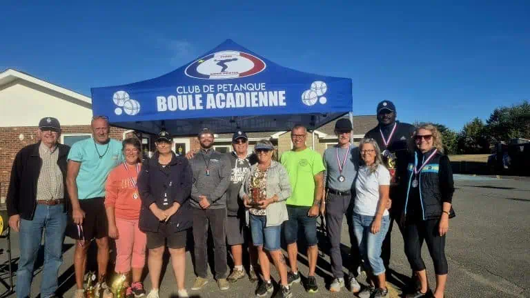 Groupe de joueurs lors d’un événement du club de pétanque Boule Acadienne sous un chapiteau bleu.