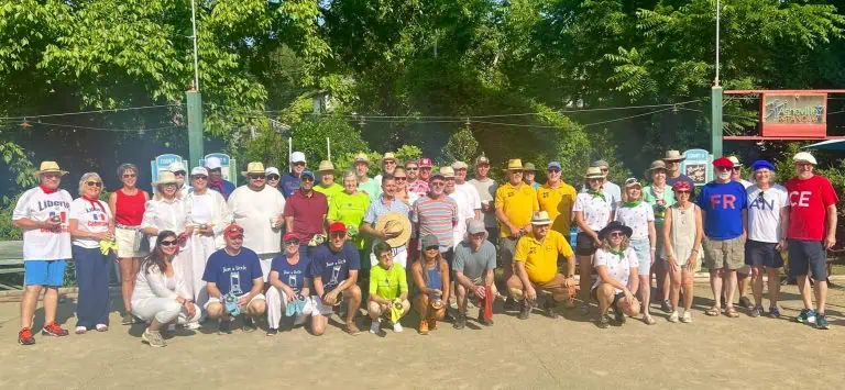 Groupe de personnes jouant à la pétanque à l’extérieur par une journée ensoleillée.