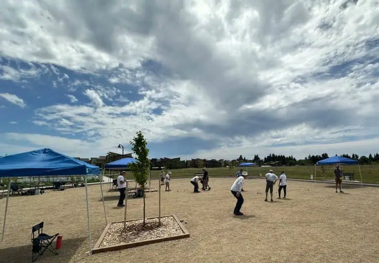 Personas jugando petanca en una cancha al aire libre bajo un cielo nublado.