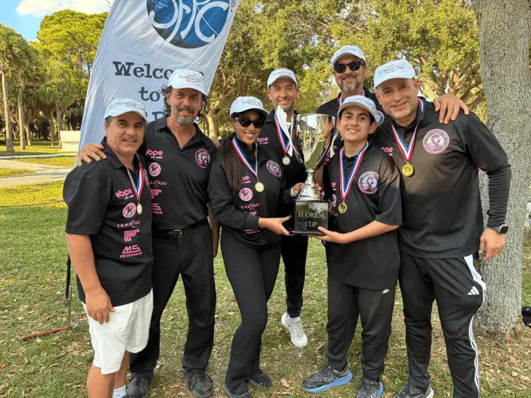 Groupe de joueurs de pétanque célébrant une victoire avec un trophée à l’extérieur dans un parc.
