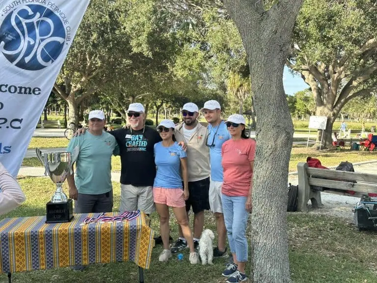 Grupo de personas celebrando un torneo de petanca al aire libre en un parque.